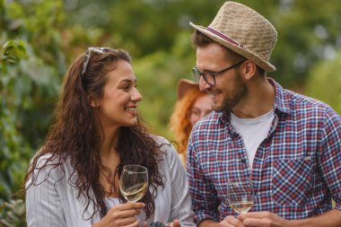 Güneşli bir öğleden sonra şarap içen gülümseyen çift.