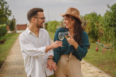 Gülümseyen bir çift el ele tutuşup şarap kadehleri tokuşturuyor.