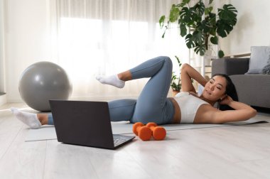 Genç bir kadın spor yapıyor, online spor dersi alıyor. 
