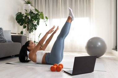 Genç bir kadın spor yapıyor, online spor dersi alıyor. 