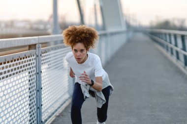 Sabahları şehir köprüsünde koşan odaklanmış bir kadın.