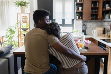 Sabah mutfak masasında kucaklaşan bir çift.