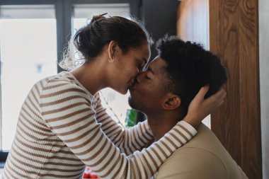 Romantik çift sıcak bir evde şefkatle öpüşüyor.