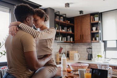 Kahvaltı sırasında modern mutfakta kucaklaşan çift