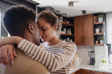 Modern mutfak ortamında şefkatle kucaklaşan çift