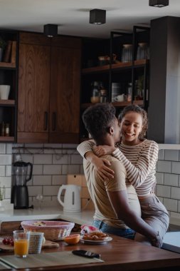 Modern mutfakta kahvaltı malzemeleriyle kucaklaşan çift.