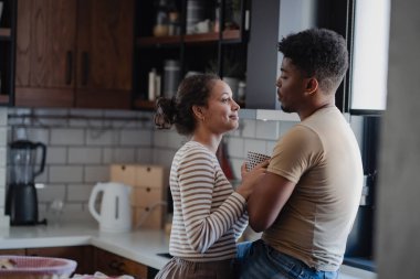 Modern dekorasyonla rahat bir mutfakta kucaklaşan çift