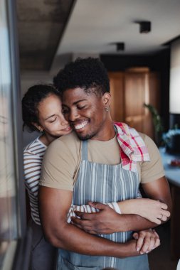 Mutfakta birbirine sarılan sıradan kıyafetler giyen bir çift.