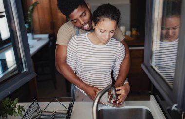 Çift sıcak mutfakta birlikte bulaşık yıkıyor.