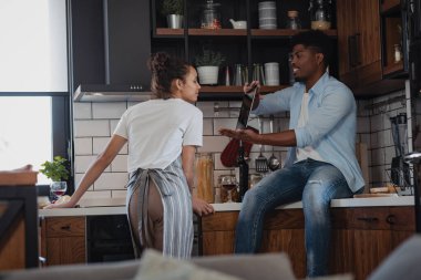 Modern mutfakta ahşap dolaplarla konuşan çift.