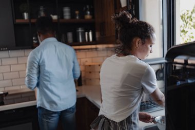 Kadın ve erkek modern mutfakta birlikte yemek pişiriyor.