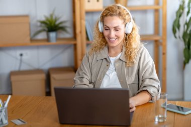 Kadın kulaklıkla çalışıyor ve dizüstü bilgisayar kullanıyor. 