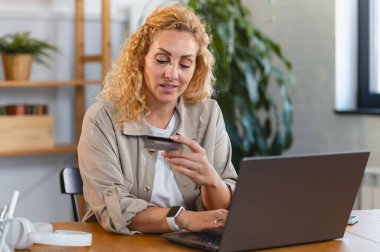 Bilgisayarı ve kredi kartı olan bir kadın internetten sipariş veriyor. 