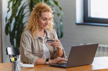 Bilgisayarı ve kredi kartı olan bir kadın internetten sipariş veriyor. 