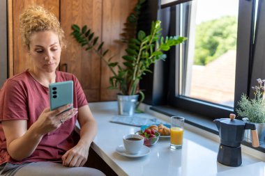 Mutfakta cep telefonu kullanan kadın. 