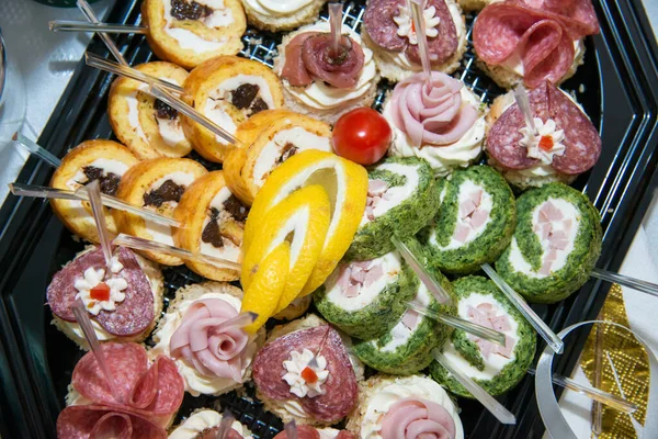 Catering food for the event - different types delicacies of meat and cheese arranged in a plate over light background - The buffet at the reception. Banquet service. Party Concept.