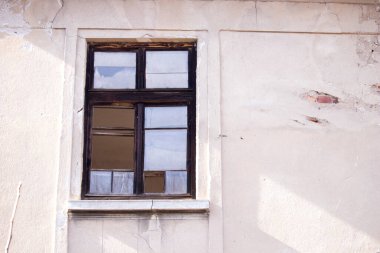 Terk edilmiş bir evin duvarında kırık camlar olan eski ahşap bir pencere.