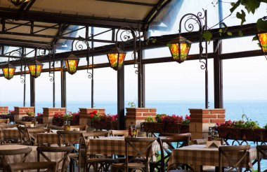 Deniz kenarında bir restoran ve teras. Renkli cam fenerler ve bir olay için hazırlanmış masalar. Seçici bir odak noktası.