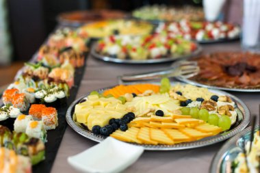 Tatil için atıştırmalıklar, yemek servisi. Çeşitli atıştırmalıklar. Salata çeşitleri, suşi ve açık büfe yemekleri. Etler, balıklar, peynir, salatalar, meyve ve sebzeler, soslar ve kanepeler bayram etkinliğini kutlamak için..