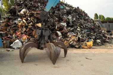 Geniş çaplı bir kazıcı metal geri dönüşüm alanında çelik bir kazıda çalışıyor. Endüstriyel metal geri dönüşümü - seçici odak, kopyalama alanı