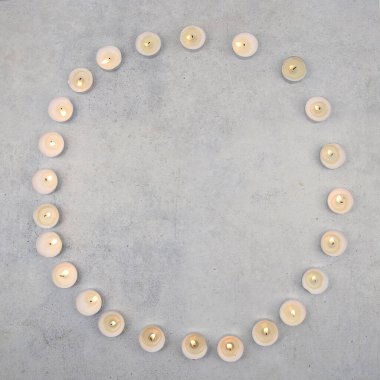 Tea light candles on stone background with copy space. Burning small candles  on cement surface, top view. clipart