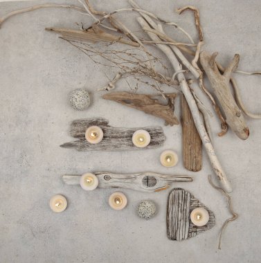 Sea driftwood pieces and tea light candles on stone background. Pieces of sea drift wood, top view. Bleached dry aged drift wood. 
