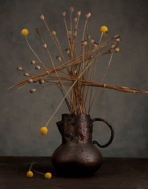 Kurumuş haşhaş ve eski pirinç sürahi vazoda craspedia ile soyut kaotik bir hayat. Koyu arkaplanda kurumuş çiçeklerin bileşimi.  