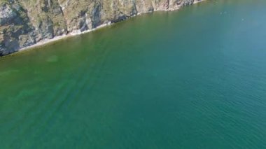 Gölün kayalık kıyısı. Doğa. Manzara. Mavi su yüzeyi. Hava aracı video görüntüleri. Üst Manzara. Yüksek kalite 4k görüntü