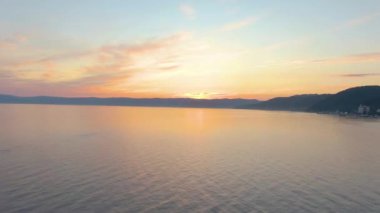Gün batımında deniz üzerinde uçuşun hava görüntüleri. Sudaki dalgalanmalar. Sahil. Üst Manzara. Bulutlar. İnsansız hava aracı görüntüleri. - Evet. Yüksek kalite 4k görüntü