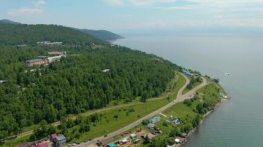 Nehir kıyısı boyunca uçuş. Sahil binaları. Yeşil Orman. Su yüzeyi. İnsan ve doğa. İHA video 4K görüntüsü. Yüksek kalite 4k görüntü