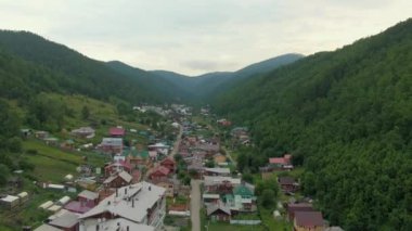 Orman tepeleri arasındaki köyün üzerinden uçuyor. Dolly zoom. İnsan ve doğa. Yeşil dağlar. Yol. Hava aracı görüntüleri. Yüksek kalite 4k görüntü