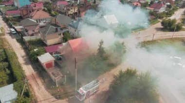 Bir yangının hava görüntüsü. Kırmızı ev. Camlardan duman çıkıyor. Konut alanı. Acil durum çağrısı. 4k drone görüntüsü. Yüksek kalite 4k görüntü