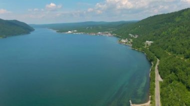 Hava aracı video görüntüleri. Nehir kıyıları arasında uçuş. Yeşil tepeler. Orman. Sahil boyunca evler ve yollar. Yüksek kalite 4k görüntü