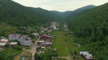 Orman tepeleri arasındaki köyün üzerinden uçuyor. İnsan ve doğa. Yeşil dağlar. Yol. Hava aracı görüntüleri. Yüksek kalite 4k görüntü
