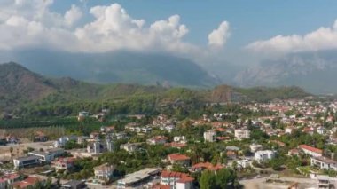 Şehrin yeşil dağların eteğindeki insansız hava aracı görüntüleri. Mavi gökyüzü. Beyaz bulutlar. Yeşil tepeler. Zaman ayarlı. Üst Manzara. Yüksek kalite 4k görüntü