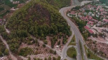 Hava aracı video görüntüleri. Dağlarda yolun üzerinden uçmak. Dağ köyü. Zaman ayarlı. Hava bulutlu. Yeşil tepeler. Yüksek kalite 4k görüntü