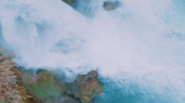 Kayanın üzerinde beyaz şelale. Drone yavaş çekim görüntüsü. Turistik bir yerde mavi bir göl. Saf su. Yüksek kalite 4k görüntü