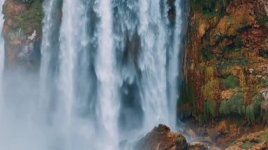 Kuşlar kırmızı bir kayanın üzerinde fırtınalı bir şelalenin önünde uçarlar. Su elementi. Vahşi yaşam konsepti. Mavi Göl. Yüksek kalite 4k görüntü