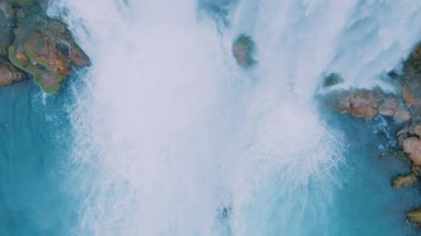 Kayanın üzerinde beyaz şelale. Drone yavaş çekim görüntüsü. Turistik bir yerde mavi bir göl. Saf su. Yüksek kalite 4k görüntü