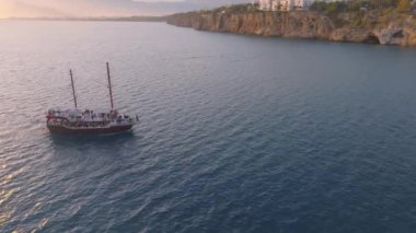 Antika yelkenli gemi gün batımında denize açılacak. Deniz Burnu. Arka planda Rocky Coast var. Bir İHA 'nın hava görüntüsü. Yüksek kalite 4k görüntü