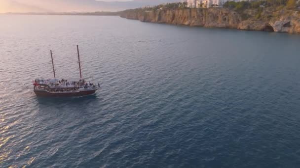 老式帆船日落时在海上航行 背景是洛基海岸无人机拍摄的空中录像高质量的4K镜头 — 图库视频影像
