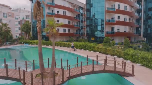 酒店院子里的无人机录像旅游度假的概念 在度假胜地度假 带着婴儿车走路的男人桥 高质量的4K镜头 — 图库视频影像