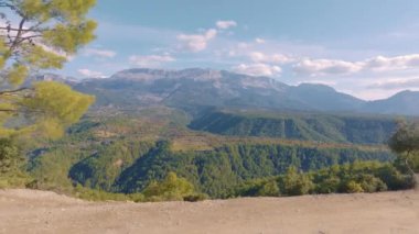 Üst Manzara. Tepelerin üzerinden uçarken çekilen hava aracı görüntüleri. Dağ manzarası. Mavi gökyüzü beyaz bulutlar. Yeşil ağaçlar. Yüksek kalite 4k görüntü