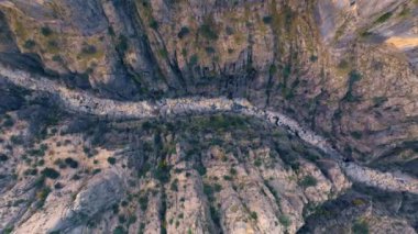 Kanyondaki bir dağ nehrinin insansız hava aracı görüntüleri. Yeşil çimenler kayaların üzerinde yetişir. Yüksek gri kayalar. Dar alan. Yüksek kalite 4k görüntü