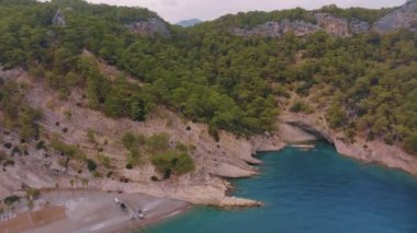 Mavi körfezdeki bir kumsalın insansız hava aracı görüntüsü. Rocky Sahili. Kayalıklardaki yeşil ağaçlar. Vahşi yaşam. Yüksek kalite 4k görüntü