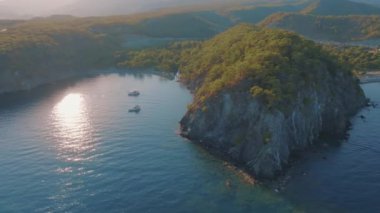 Körfezin üst manzarası, kayalık kıyı, yeşil ağaçlar ve yatlar. Deniz Burnu. Temiz, sakin su. Bir İHA 'nın hava görüntüleri. Yüksek kalite 4k görüntü