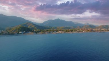Mavi deniz üzerindeki İHA uçuşunun hava görüntüleri. Arka planda sahil ve dağlar var. Dramatik bir gökyüzü. Deniz Burnu. Güzel gün batımı. Yüksek kalite 4k görüntü