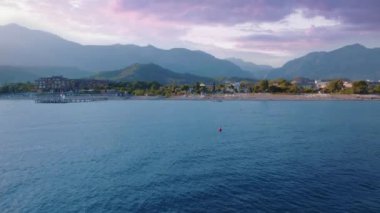 Güzel gün batımı. Mavi deniz üzerindeki İHA uçuşunun hava görüntüleri. Arka planda sahil ve dağlar var. Deniz Burnu. Şamandıra. Yüksek kalite 4k görüntü