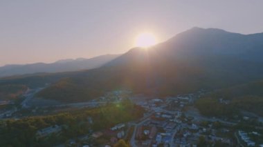 Hava aracı video görüntüleri. Dağların arkasındaki tatil köyü. Gün batımı gökyüzü. Arka planda dağlar. Yüksek kalite 4k görüntü