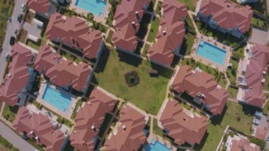 Bölgenin yukarısından bir manzara. Bungalov çatıları, yüzme havuzları, yeşil çimenler ve palmiye ağaçları. Hava aracı video görüntüleri. Yüksek kalite 4k görüntü